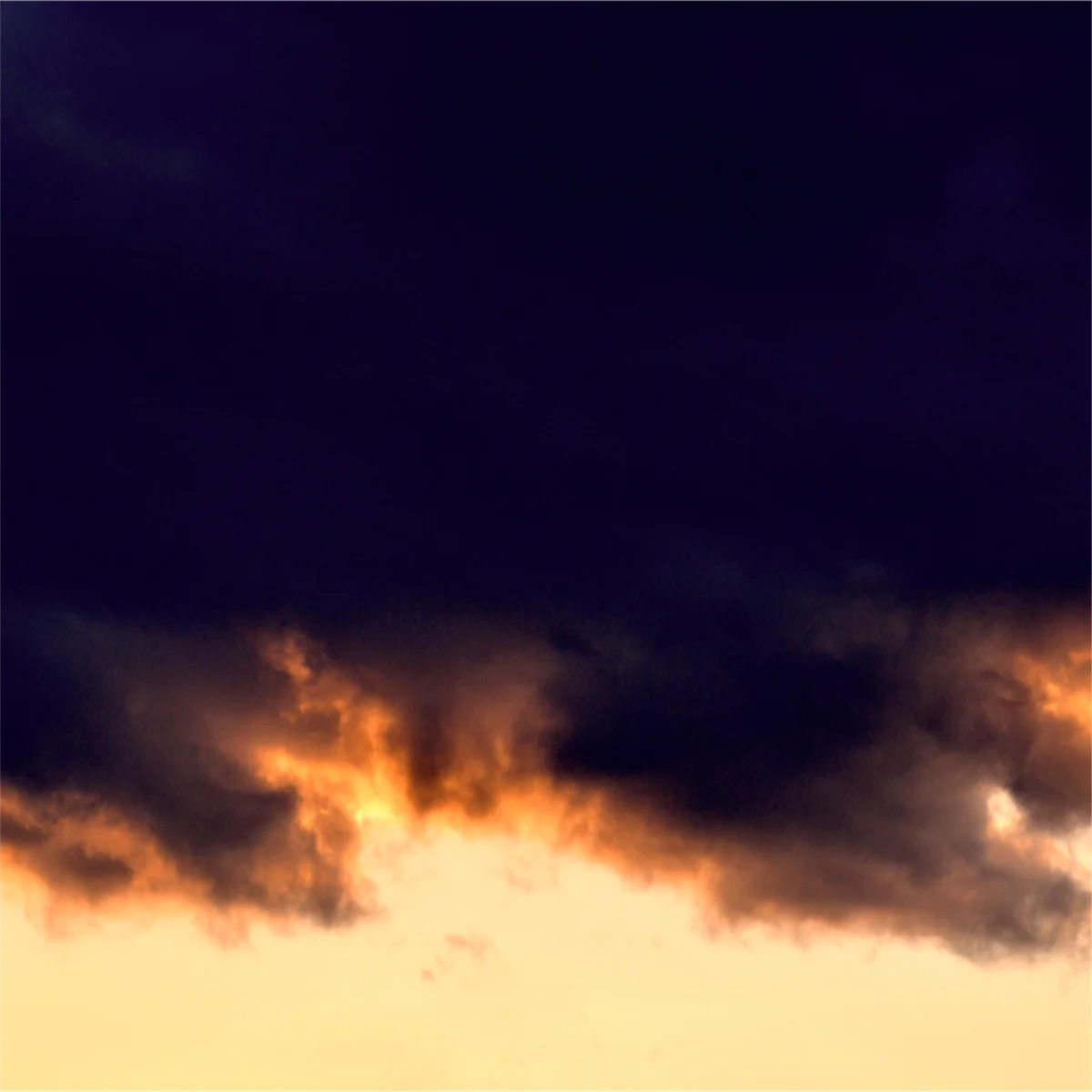 オレンジ色の空に浮かぶ黒い雲の写真