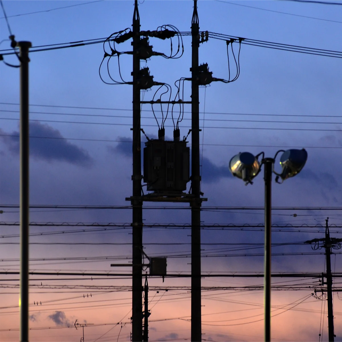 鉛色からオレンジ色へのグラデーションの空を背景にした電柱
