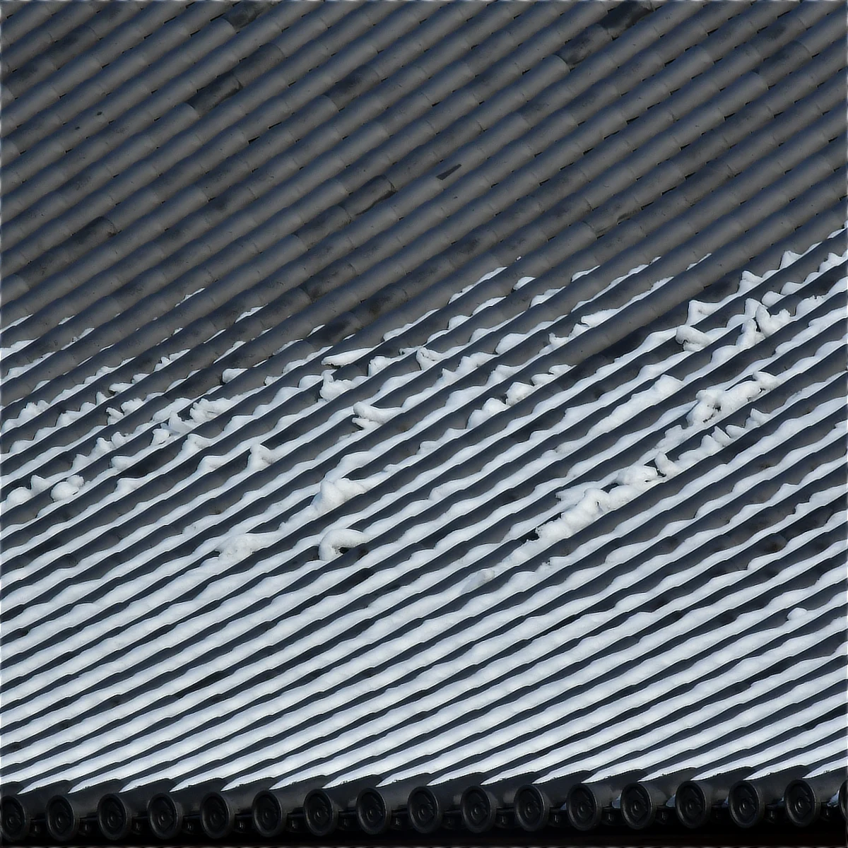 大きな瓦屋根の凹んだ部分に雪が残っている