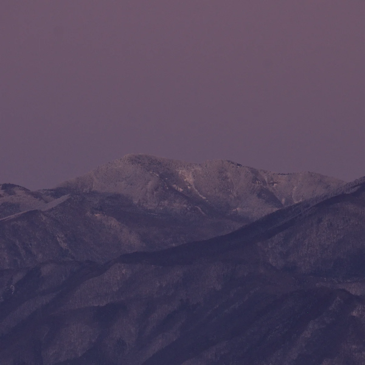 夕暮れの山と空がピンク色に染まっている